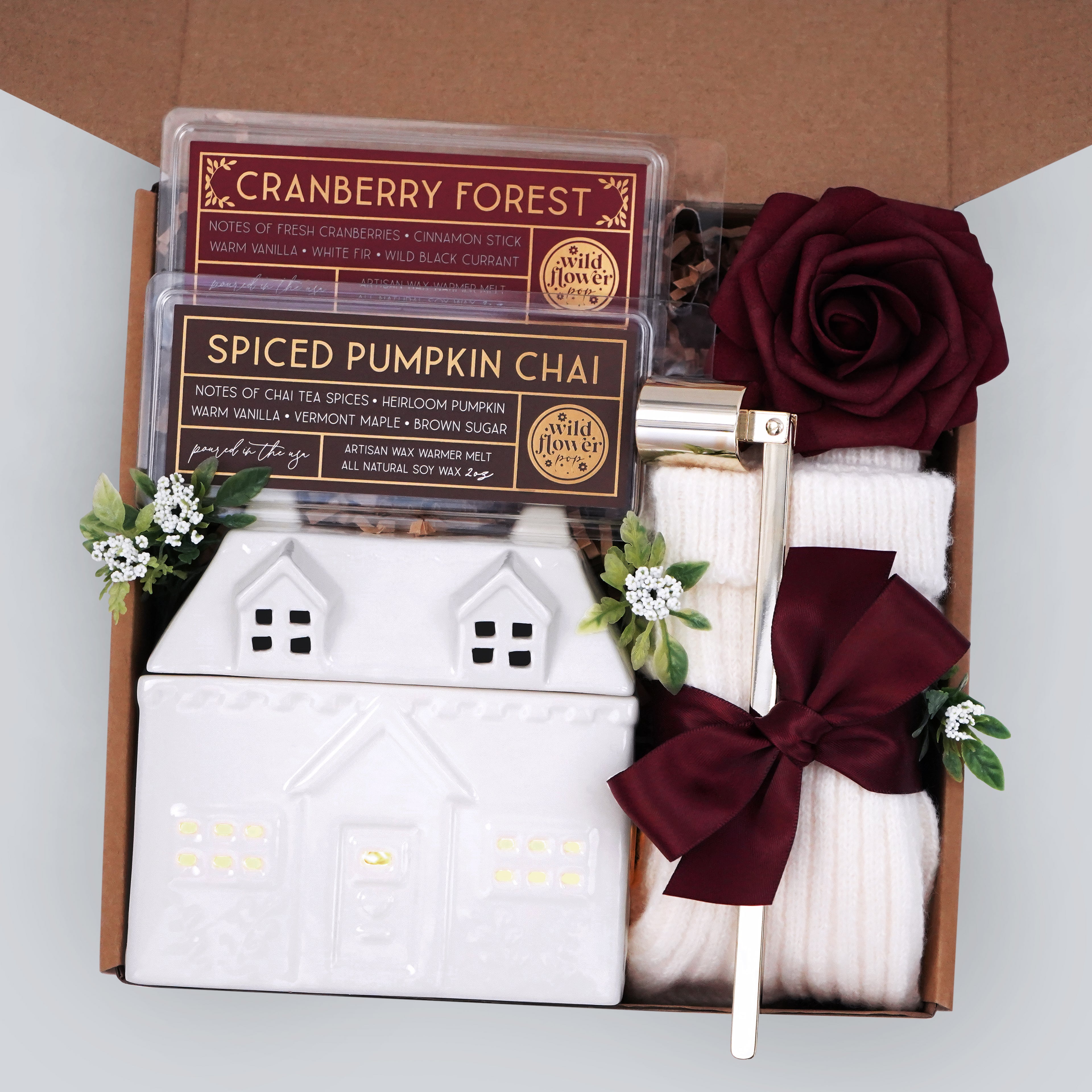 Wildflower Pop exclusive cottage wax warmer, 2 made in the USA 100% soy wax melts, gold candle snuffer, tea light, cream knit socks, with a burgundy faux rose. Packaged and ready to gift.
