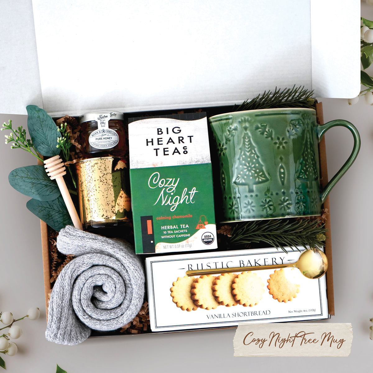 Cozy Night Tree Mug Box comes with a nordic tree ceramic mug, rustic bakery vanilla shortbread cookies, gold demitasse spoon, mini honey and dipper, cozy night 10 count tea bags, cozy boot socks, and gold votive and tea light 
