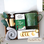 Cozy Night Tree Mug Box comes with a nordic tree ceramic mug, rustic bakery vanilla shortbread cookies, gold demitasse spoon, mini honey and dipper, cozy night 10 count tea bags, cozy boot socks, and gold votive and tea light 