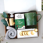 Cozy Night Tree Mug Box comes with a nordic tree ceramic mug, rustic bakery vanilla shortbread cookies, gold demitasse spoon, mini honey and dipper, cozy night 10 count tea bags, cozy boot socks, and gold votive and tea light 