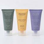 Three squeeze tubes of deep steep Clean Beauty body lotion lined up on a white background. From left to right Rosemary Mint scent, Grapefruit Bergamot scent, and Lavender Chamomile scent.