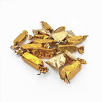 A pile of wrapped candies or chocolates individually wrapped in shiny metallic gold foil, arranged on a plain white background.