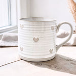 Wildflower Pop Exclusive Designed by us White mug with heart patterns on a textured beige surface