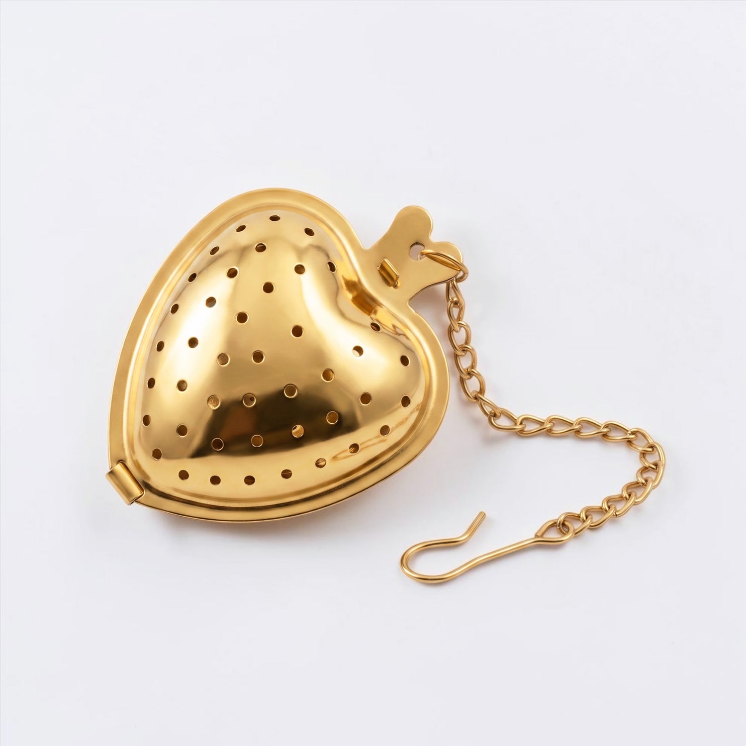A gold-colored metal heart-shaped tea infuser with a matching chain, shown on a clean white background.
