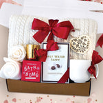 Hello Cupid Gift Box comes with a cream cable knit blanket tied with a red ribbon, cream knit socks, gold votive and tea light, Seaberry and Rose bath bomb, Chocolate Chiffon salt water taffy, nordic heart wood ornament, faux rose head, and cream ribbed mug