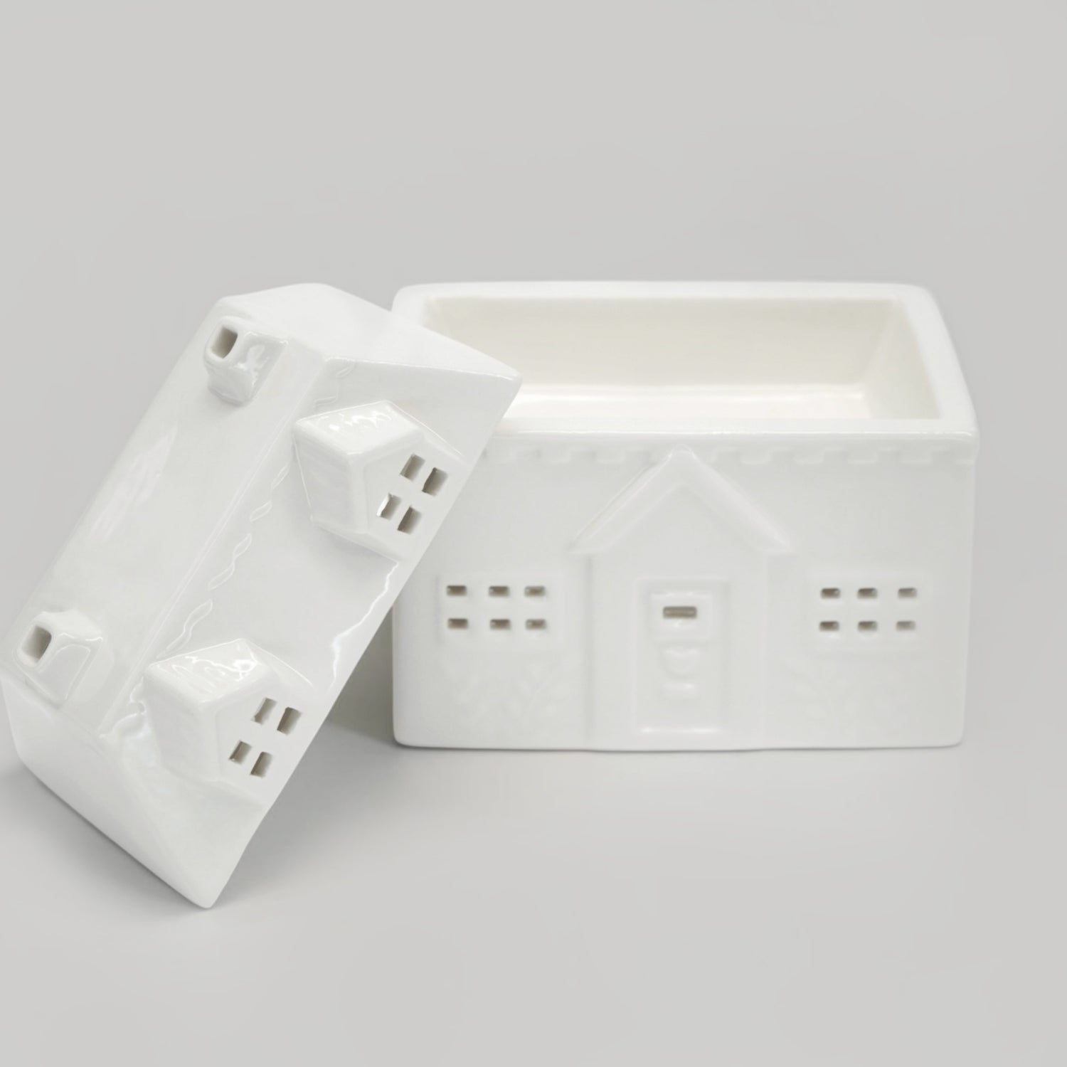 A white ceramic house-shaped wax warmer on a light gray background.