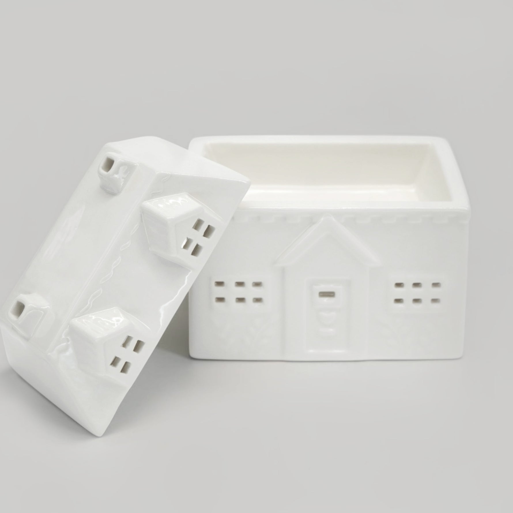 A white ceramic house-shaped wax warmer on a light gray background.