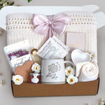 Love you mama blanket box comes with a cream lace knit blanket tied in a blush ribbon, 2 tea with tae tea bags, gold demitasse spoon, rose seaside soak bath salts, heart coaster, mini honey, mama ceramic mug, heart trinket dish, full size moonstruck milk chocolate bar, and cream knit socks