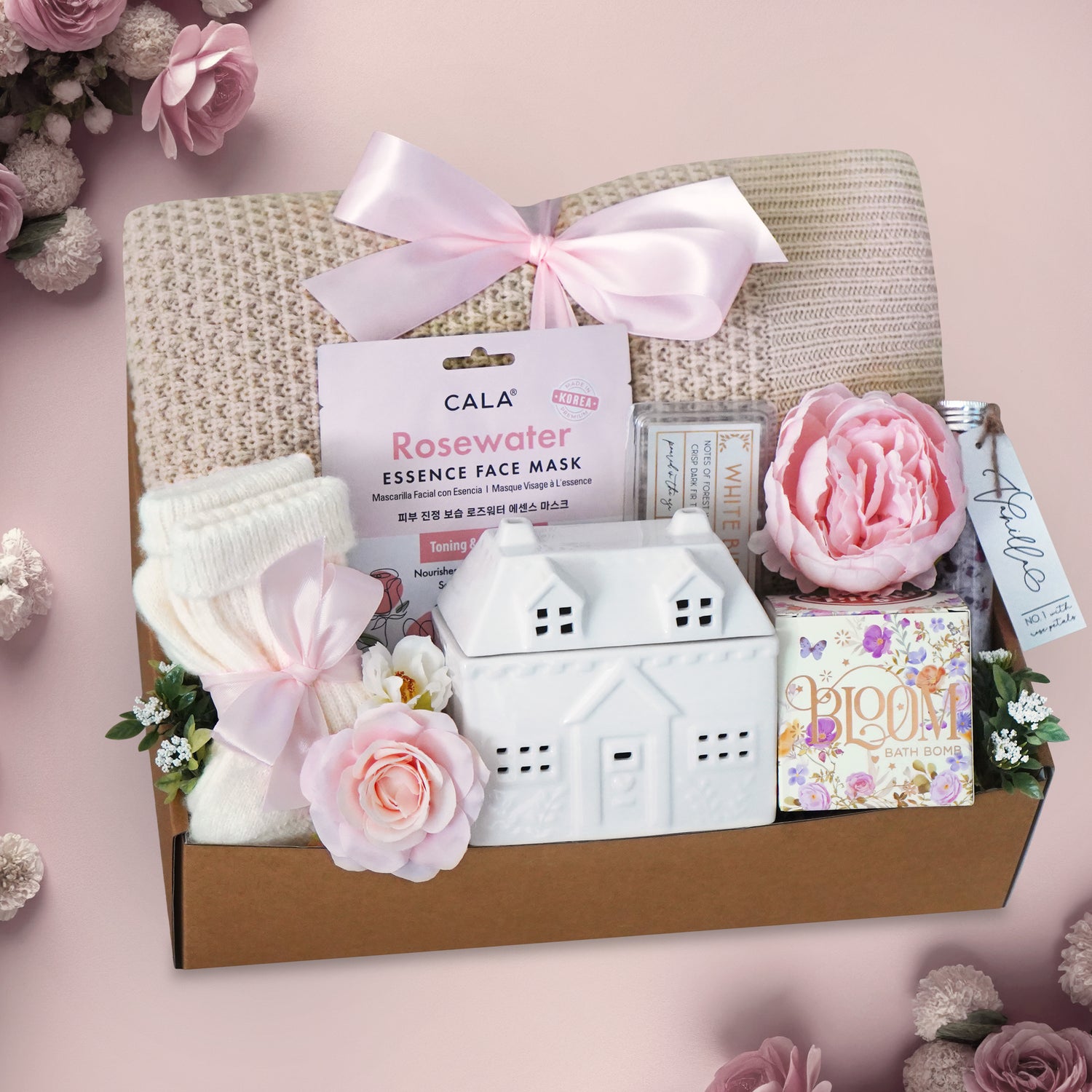 Wildflower Pop Cottage in Bloom Gift box with beauty products, flowers, and a pink bow on a pink background