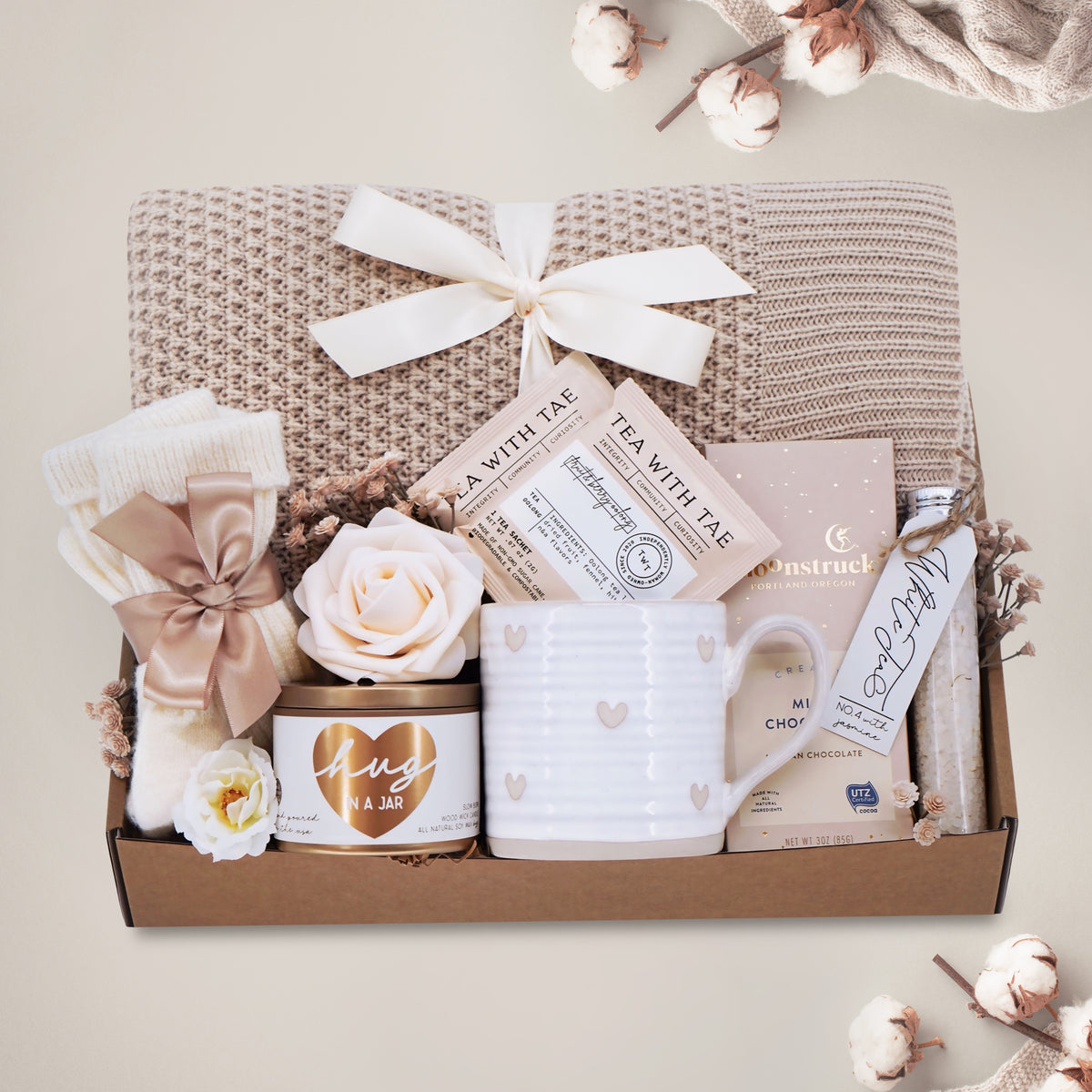 Wildflower Pop Hugs for You Blanket Gift Box comes with honeycomb blanket, cream knit socks, hug in a jar soy wax candle, Wildflower Pop Hearts ceramic mug, 2 tea bags, Moonstruck milk chocolate bar, and floral bath salts