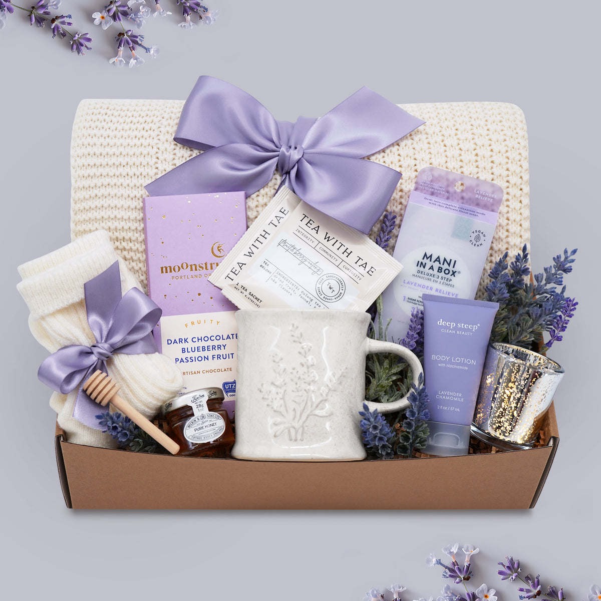 Lavender Garden blanket gift box by Wildflower Pop comes with cream lace knit blanket, mani kit, chocolate bar, cream knit socks, mini honey and dipper, Lavender Mug by Wildflower Pop, Lavender body lotion, silver votive with tea light 