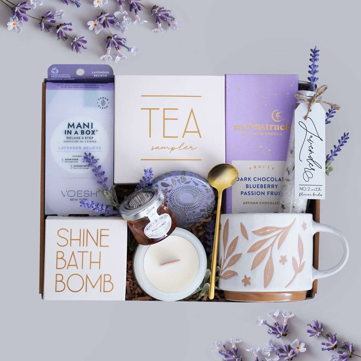 Wildflower Pop Gift set with tea, chocolate, candle, and bath bomb on a light gray background with lavender flowers.