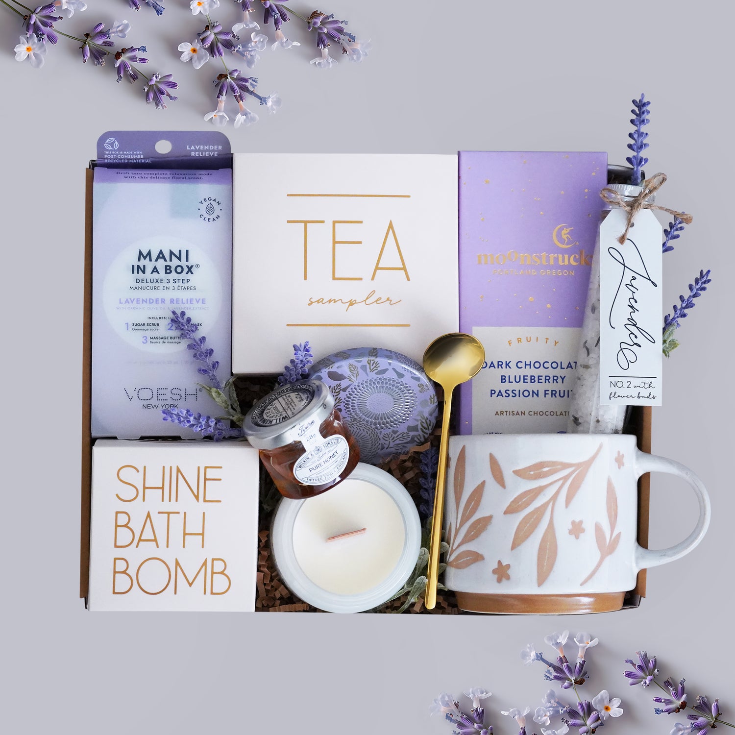 Wildflower Pop Gift set with tea, chocolate, candle, and bath bomb on a light gray background with lavender flowers.