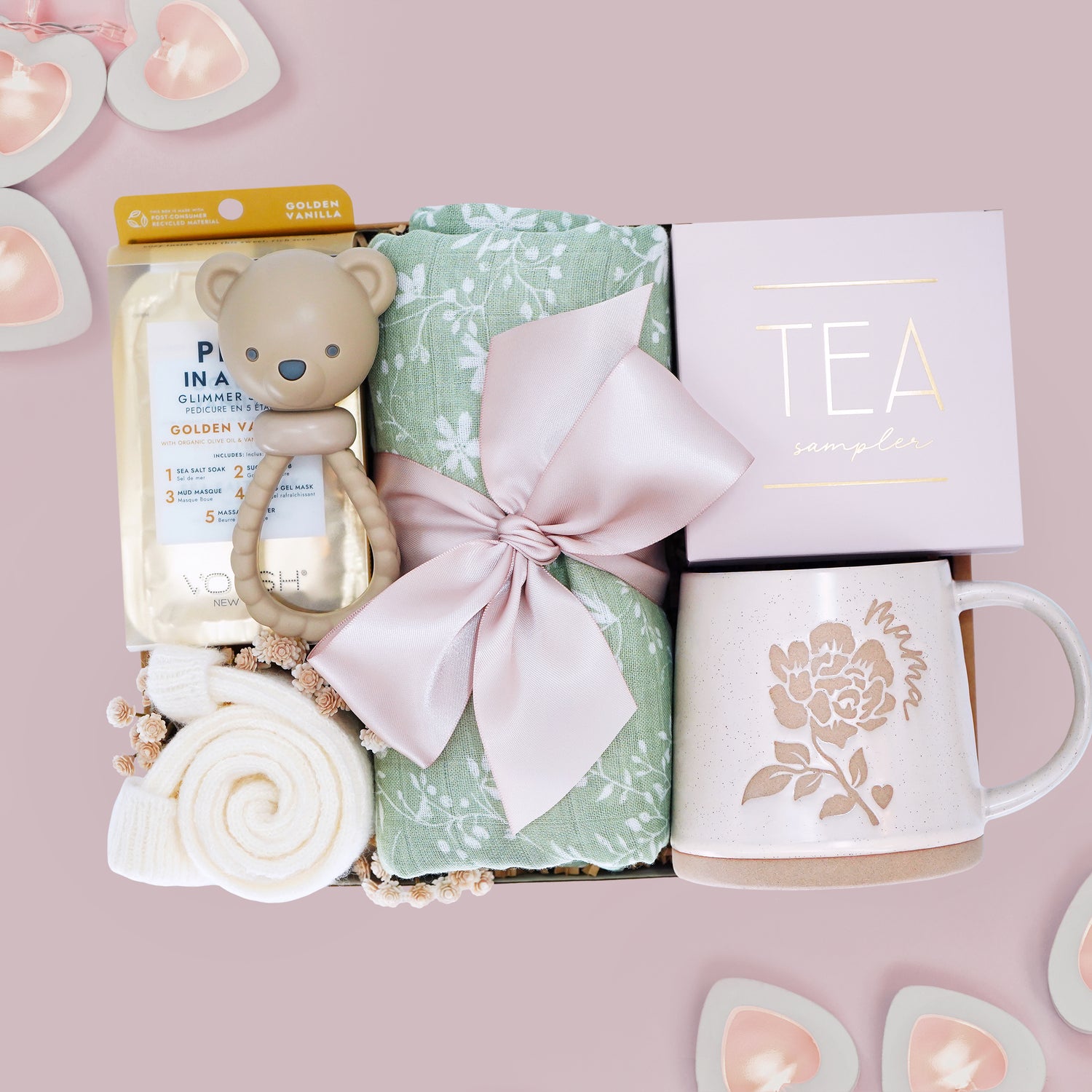 M is for Mama new mom gift set from Wildflower Pop comes with a sage green botanical swaddle, bear rattle, pedi kit, cream socks, tea sampler, and Wildflower Pop designed Peony Mama mug
