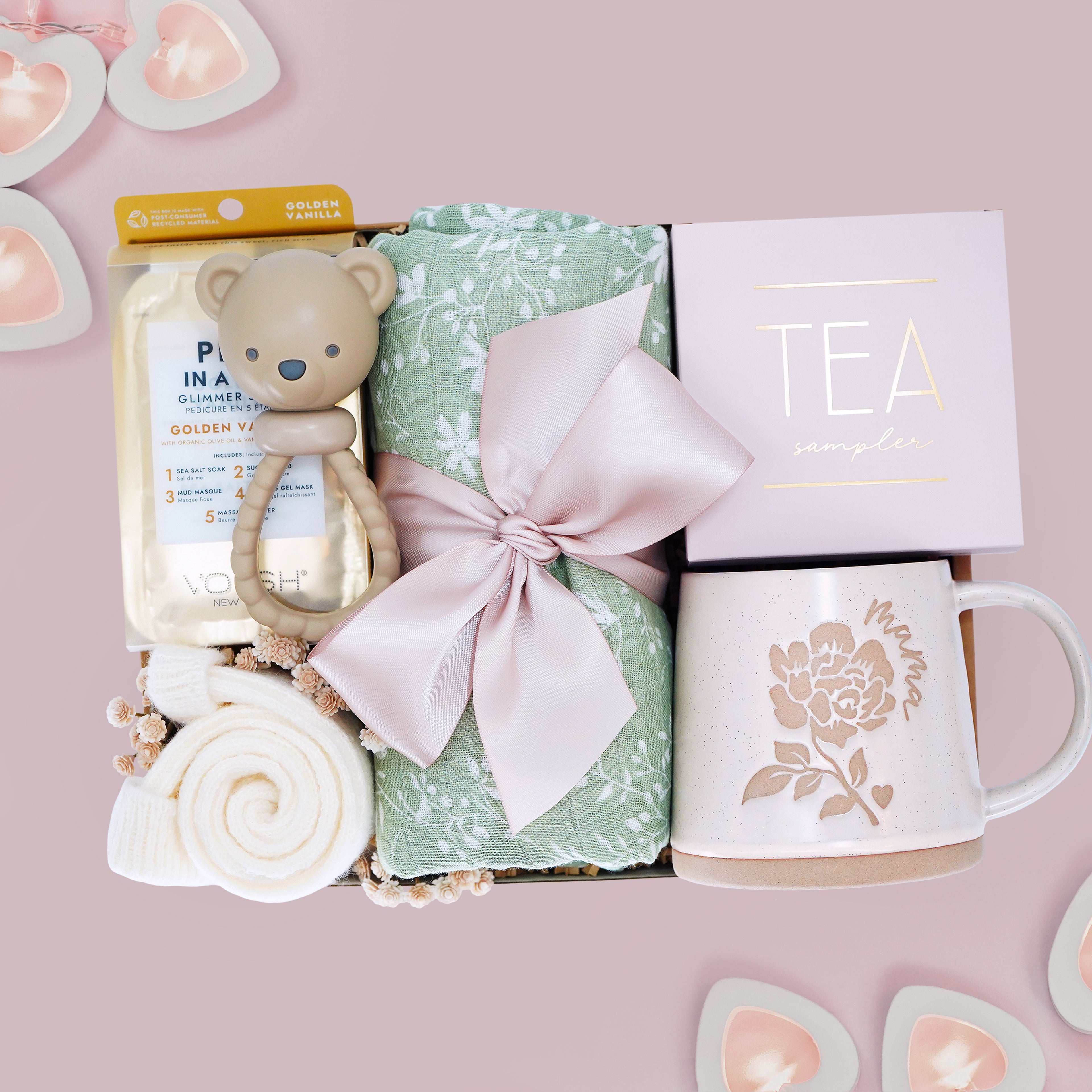 M is for Mama new mom gift set from Wildflower Pop comes with a sage green botanical swaddle, bear rattle, pedi kit, cream socks, tea sampler, and Wildflower Pop designed Peony Mama mug