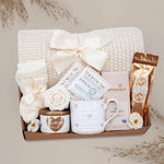 Wildflower Pop Sending a Hug Blanket gift box, with cream lace knit blanket, tea sampler, cream knit socks, hug in a jar soy wax candle, Wildflower Pop Heart ceramic mug, Moonstruck Milk Chocolate bar, and muscle soak