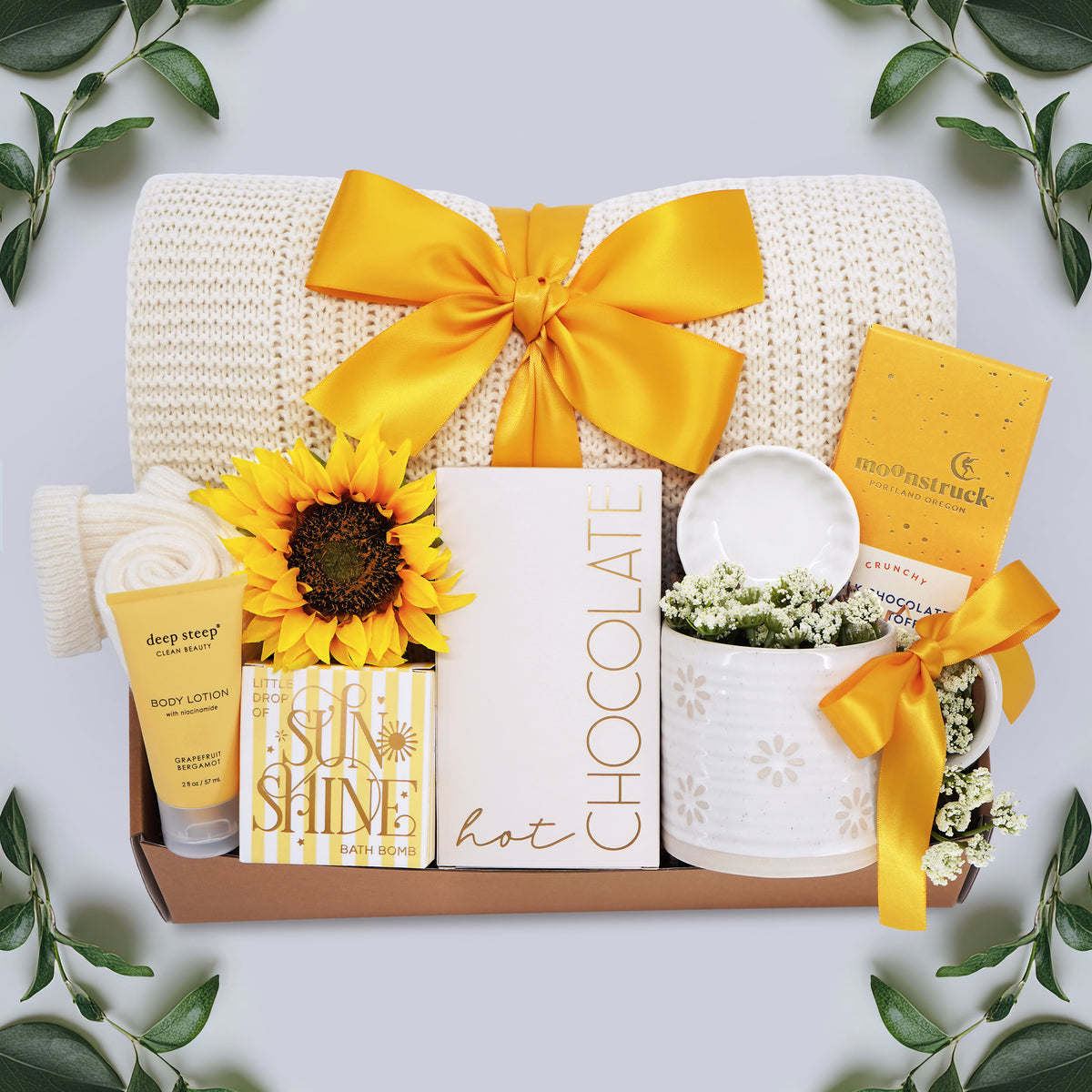 Wildflower Pop Sunny Days Ahead blanket gift box with a cream lace knit blanket, Wildflower Pop daisy ceramic mug, scallop trinket dish, moonstruck milk chocolate and toffee bar, little drop of sunshine bath bomb, faux sunflower, deep steep lotion, and cream knit socks