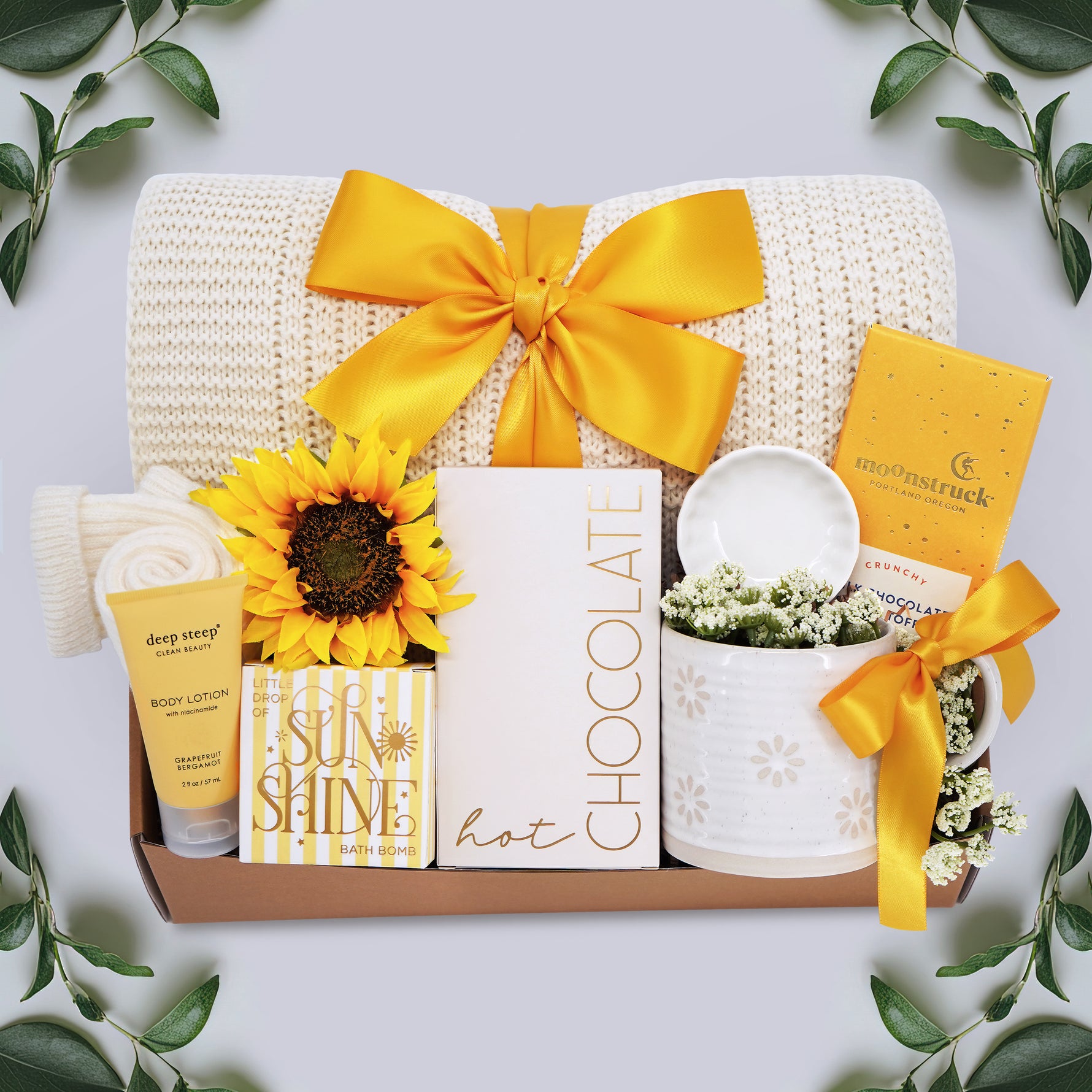 Wildflower Pop Sunny Days Ahead blanket gift box with a cream lace knit blanket, Wildflower Pop daisy ceramic mug, scallop trinket dish, moonstruck milk chocolate and toffee bar, little drop of sunshine bath bomb, faux sunflower, deep steep lotion, and cream knit socks
