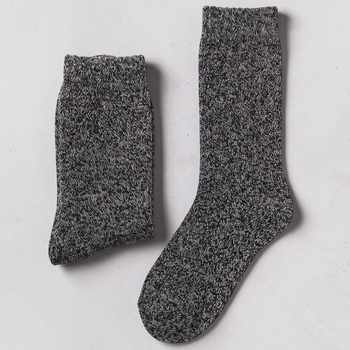 A pair of dark gray mens heathered knit crew socks laid flat on a light gray surface.
