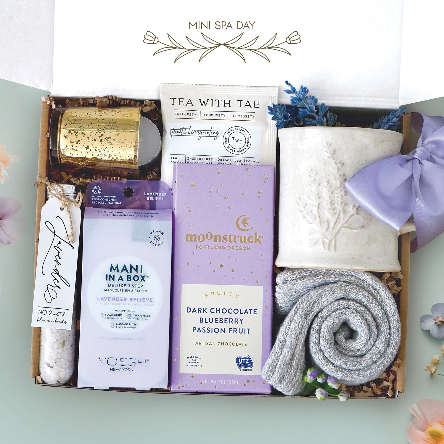 Mini spa day mug box comes with a lavender ceramic mug, votive and candle, mani in a box kit, lavender bath salt tube, moonstruck dark chocolate and blueberry bar, tea with tae tea bags, cozy boot socks, and faux lavender sprig