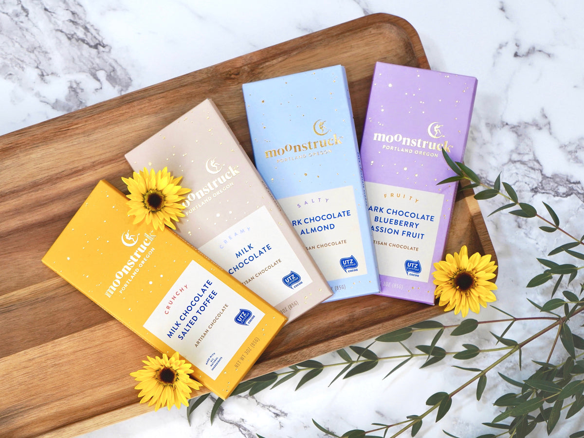 Moonstruck Chocolate bar in a variety of flavors each bar is 3oz, shown is milk chocolate salted toffee, milk chocolate, dark chocolate almond, and dark chocolate blueberry and passionfruit 