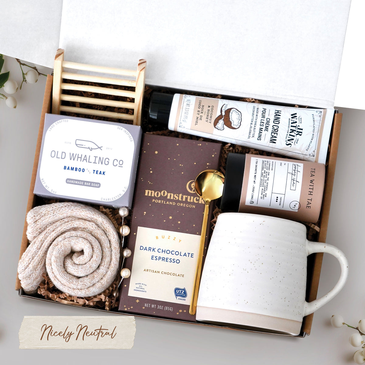 The Nicely Neutral Mug Gift Box comes with a ceramic beehive mug, old whaling co bamboo and teak bar of soap, cozy boot socks, bamboo soap rack, moonstruck espresso dark chocolate bar, gold spoon, tea tube with 5 tea bags, and coconut and honey hand cream 3.3 oz