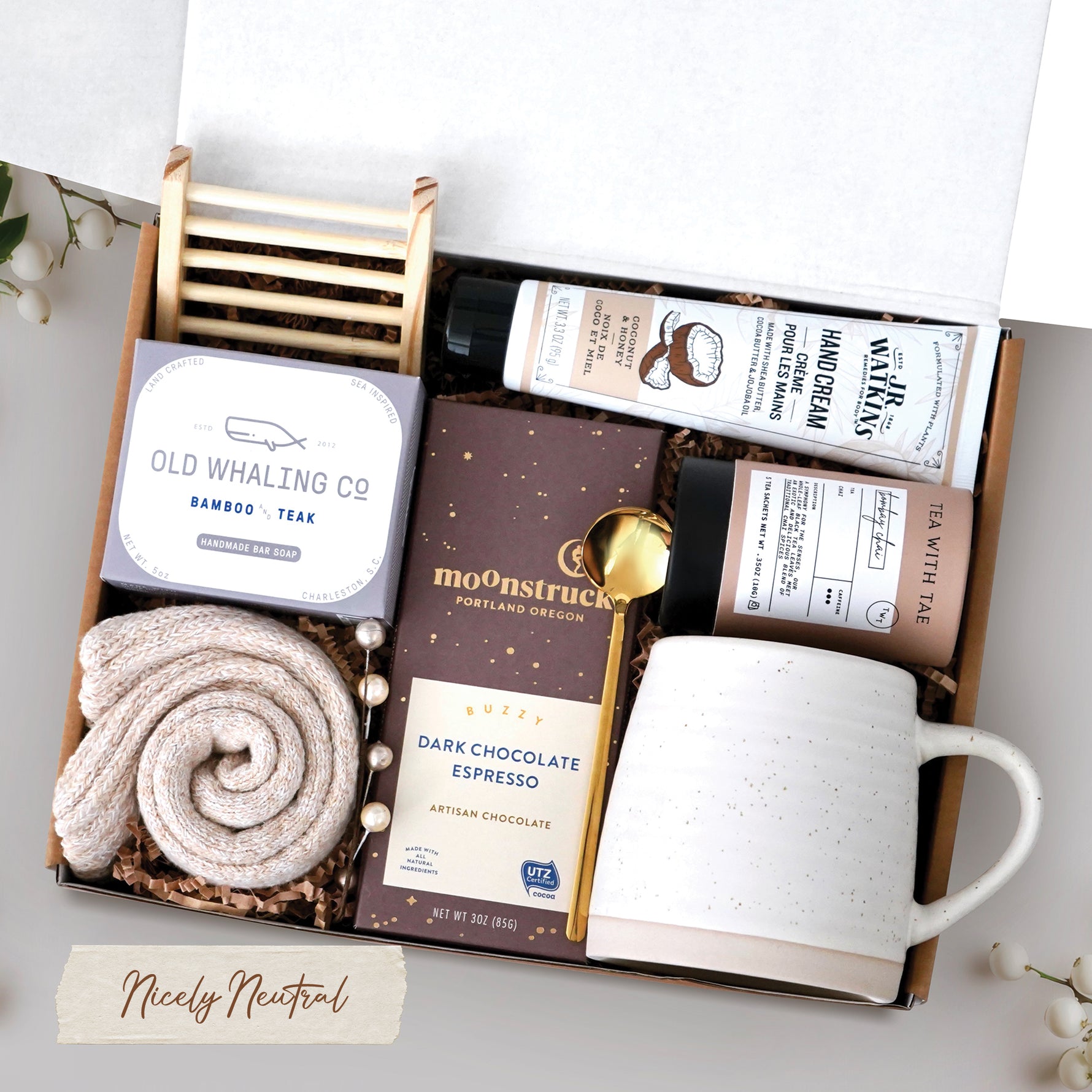 The Nicely Neutral Mug Gift Box comes with a ceramic beehive mug, old whaling co bamboo and teak bar of soap, cozy boot socks, bamboo soap rack, moonstruck espresso dark chocolate bar, gold spoon, tea tube with 5 tea bags, and coconut and honey hand cream 3.3 oz