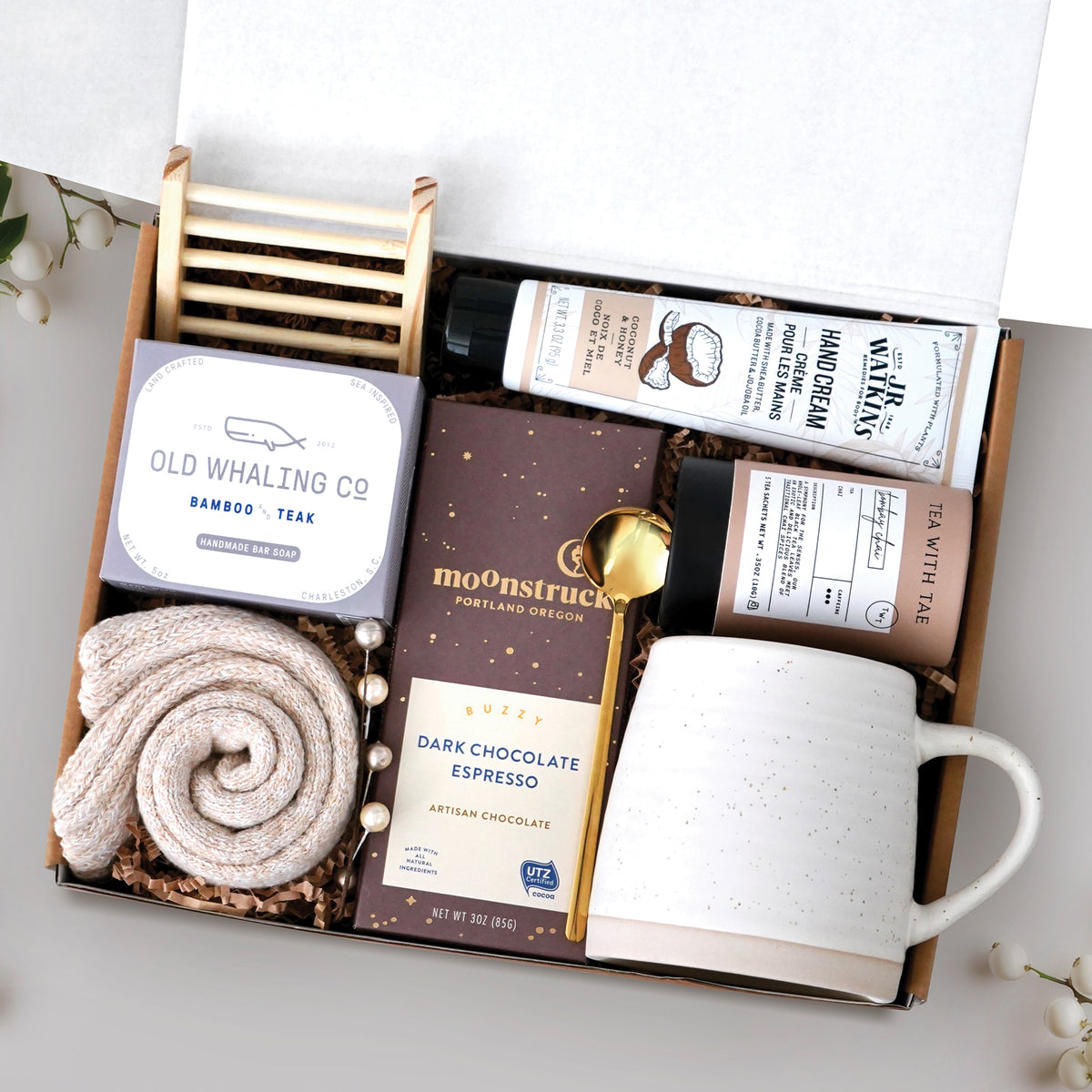 The Nicely Neutral Mug Gift Box comes with a ceramic beehive mug, old whaling co bamboo and teak bar of soap, cozy boot socks, bamboo soap rack, moonstruck espresso dark chocolate bar, gold spoon, tea tube with 5 tea bags, and coconut and honey hand cream 3.3 oz
