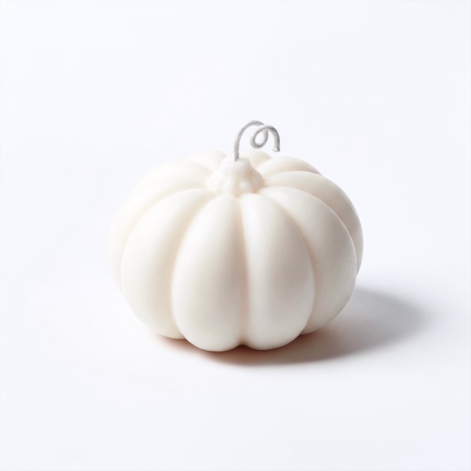 A small white pumpkin-shaped candle set against a clean white background.