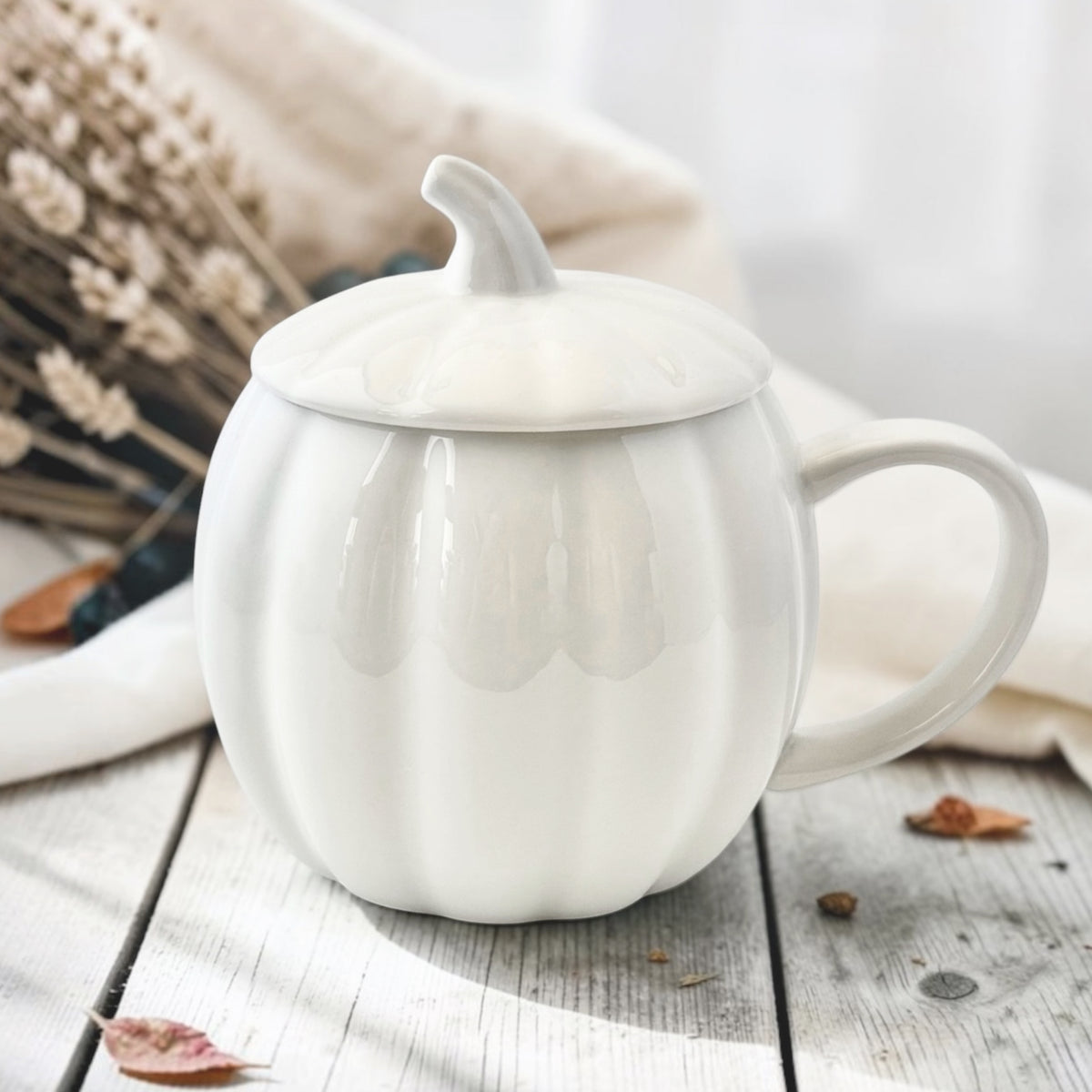 White ceramic pumpkin mug with stem lid on wooden background