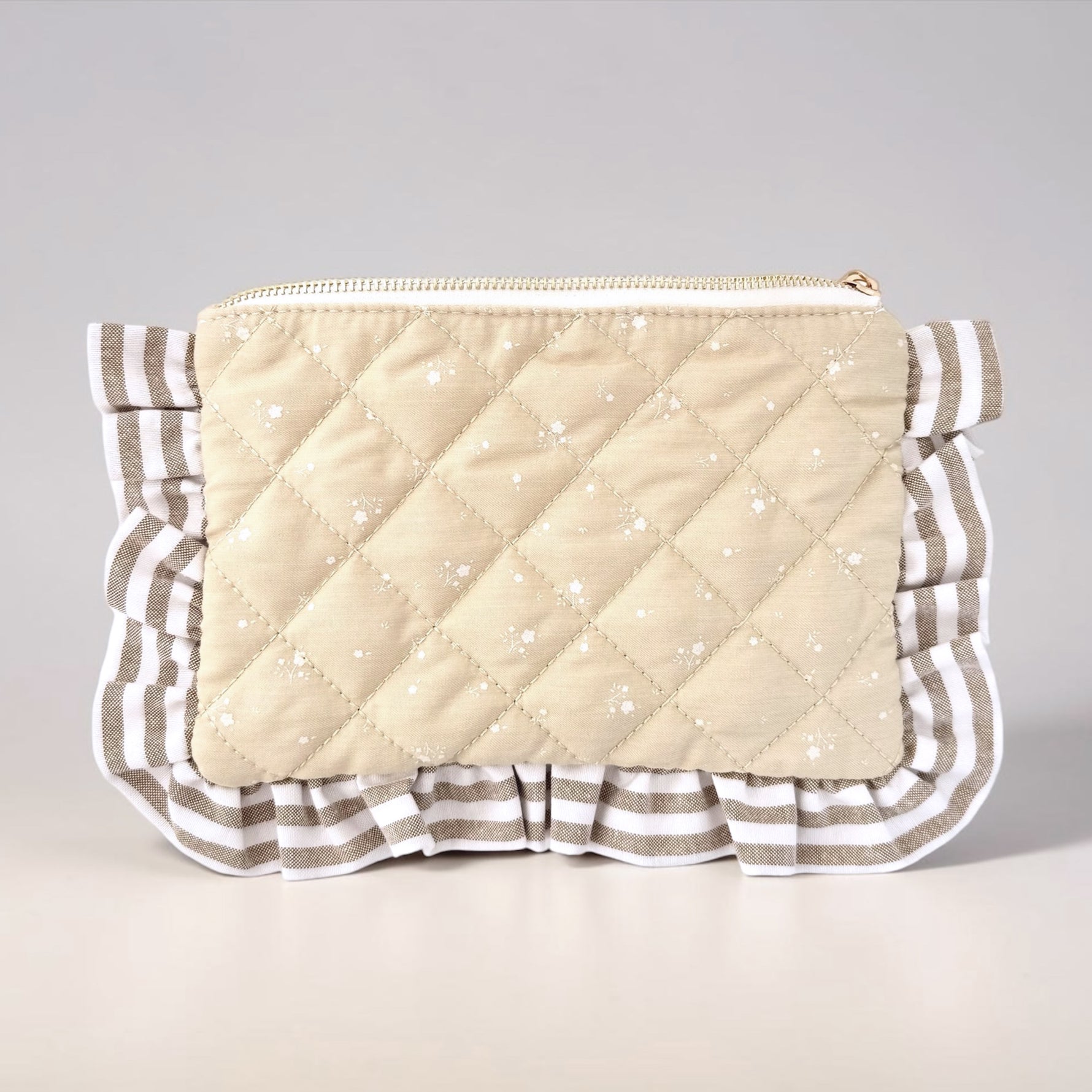 Quilted pouch with ruffled edge on a light gray background