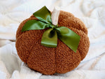 Sherpa Pumpkin Pillow in Orange tied with a moss green bow, measures around 10"