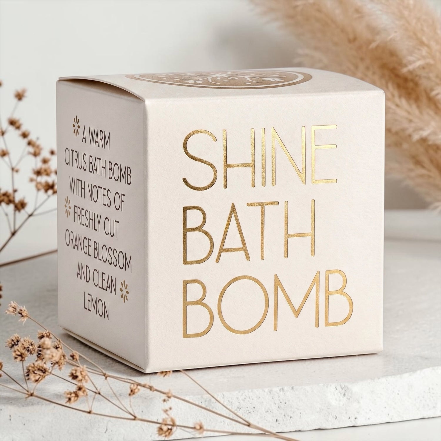 Wildflower Pop Shine Bath Bomb in a cream box with gold foil, a warm citrus scent with notes of orange blossom and lemon.