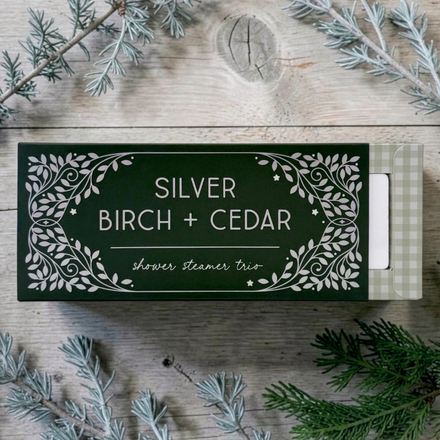 A boxed shower steamer set labeled SILVER BIRCH + CEDAR scent on a rustic wood surface.