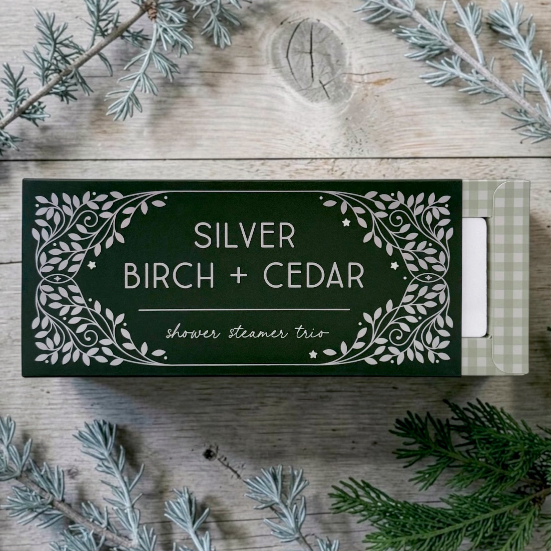 A boxed shower steamer set labeled SILVER BIRCH + CEDAR scent on a rustic wood surface.