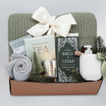 Wildflower Pop Silver Forest Blanket gift box, with sage green lace knit blanket, cream ribbed ceramic mug, grey cozy boot socks, silver votive and tea light, mini honey and dipper, silver birch and cedar shower steamers, and tea sampler