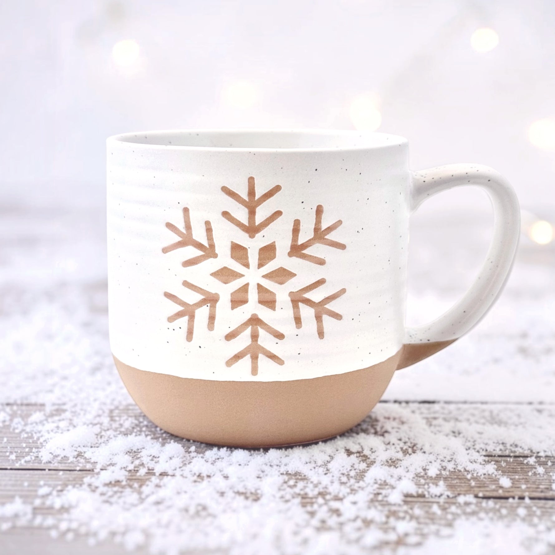 Rustic ceramic snowflake mug with white speckle glaze on winter background
