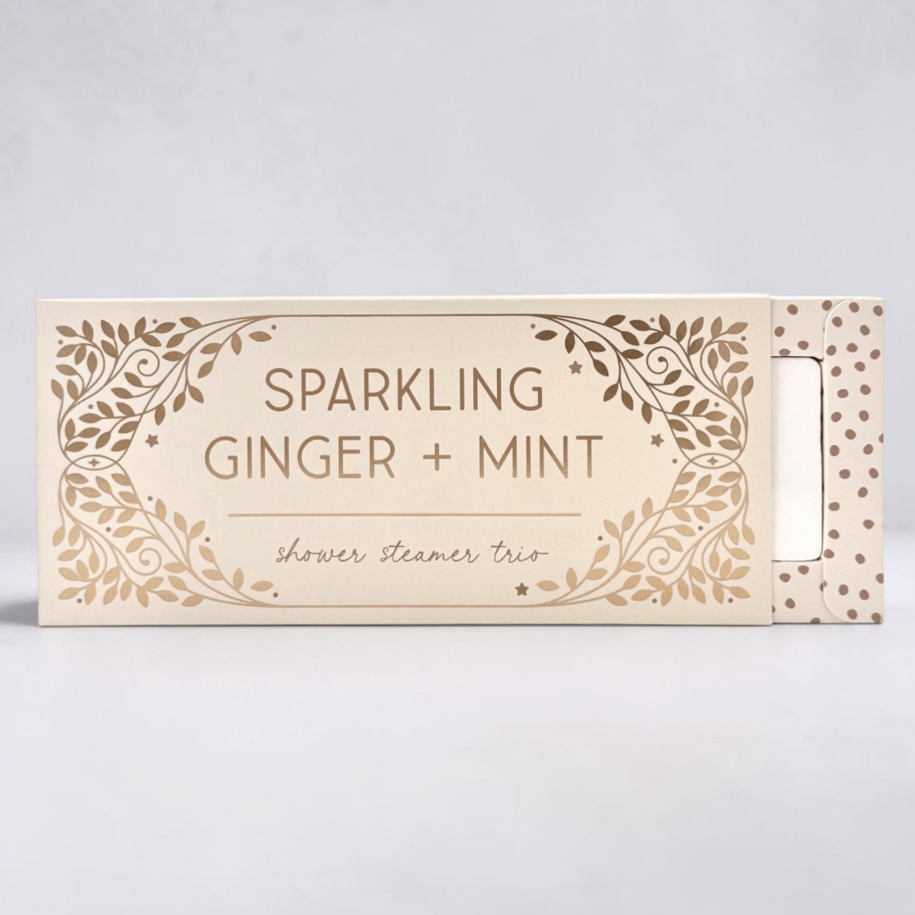 Box of sparkling ginger and mint shower steamer trio on a light gray background