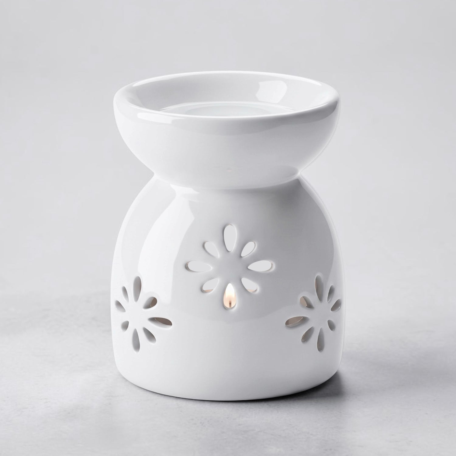A white ceramic wax warmer/diffuser with a starburst cutout pattern, set against a light gray background.
