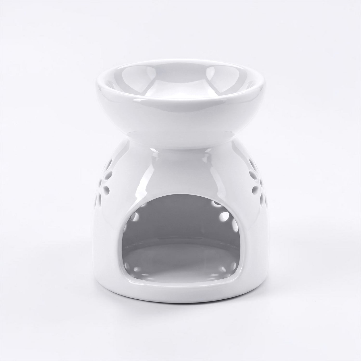 A white ceramic wax warmer/diffuser with a starburst cutout pattern, set against a light gray background.