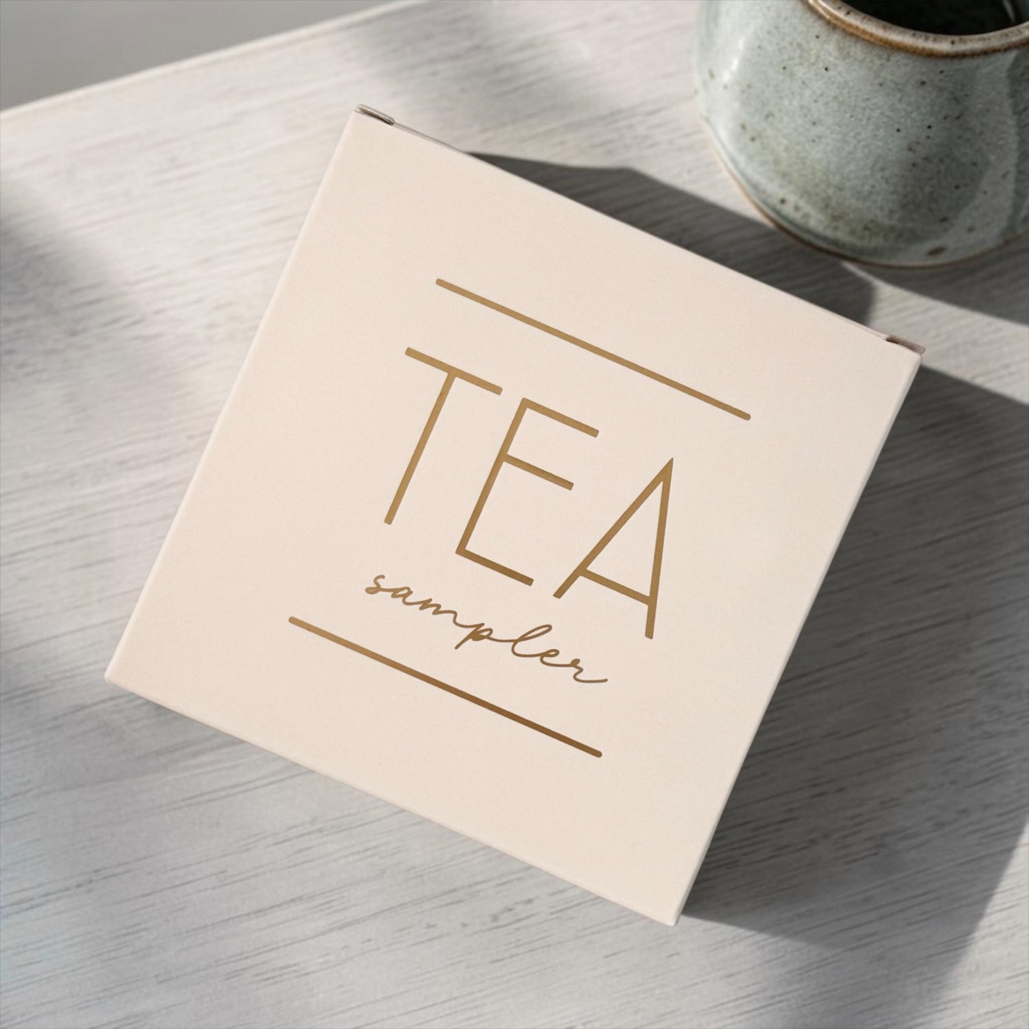 Tea sampler box on a wooden surface with a ceramic mug in the background