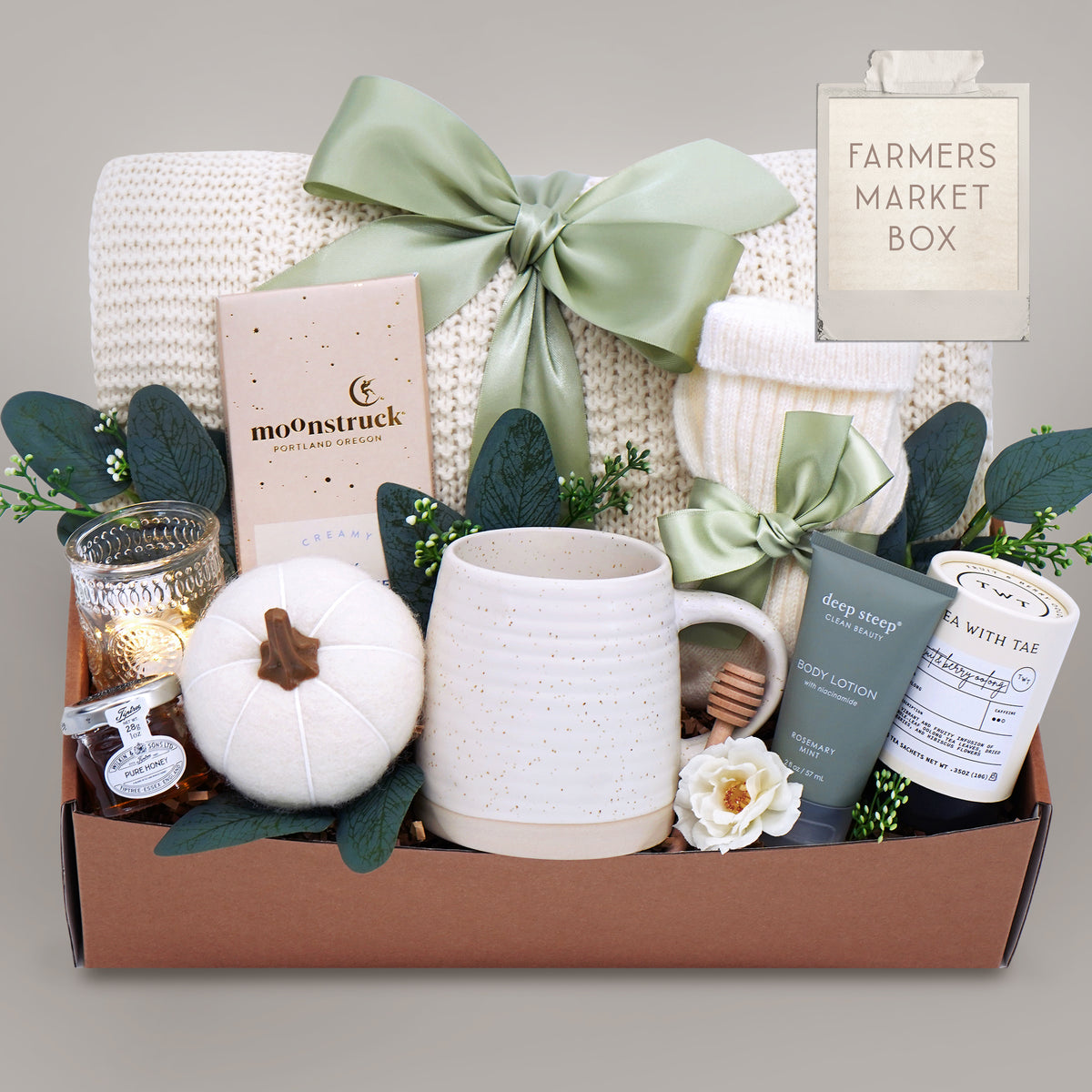 Gift box with a mug, candle, and other items on a gray background