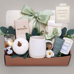 Gift box with a mug, candle, and other items on a gray background