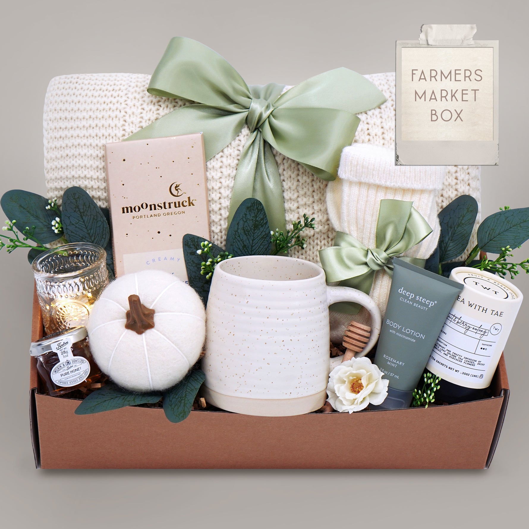 Gift box with a mug, candle, and other items on a gray background