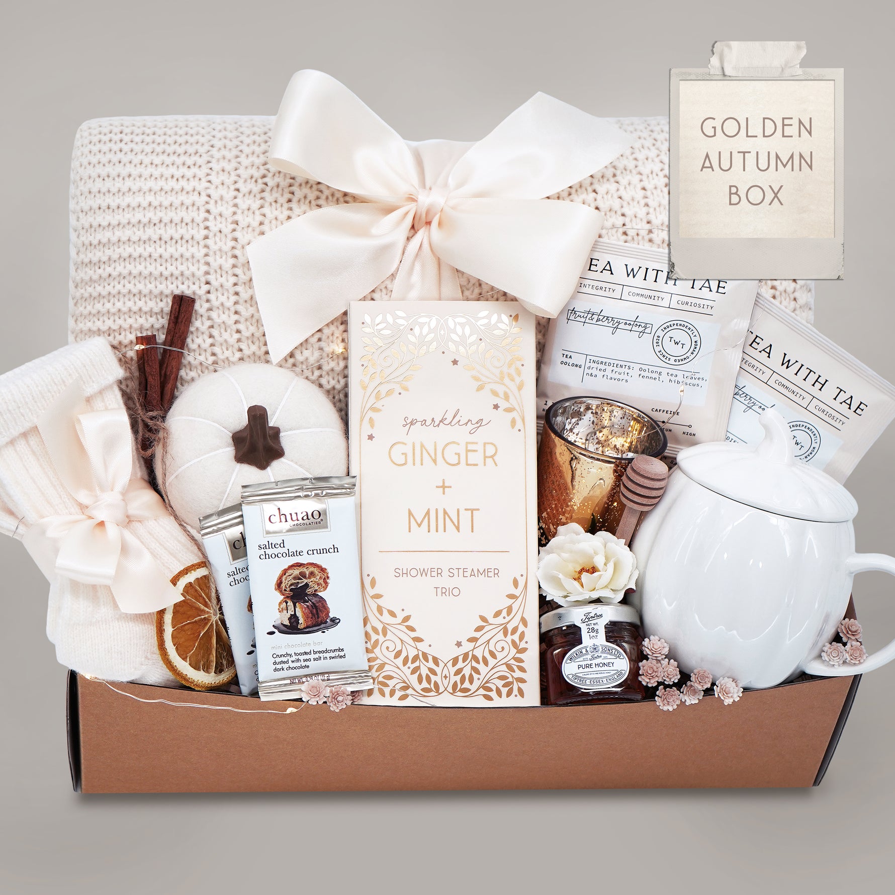 Gift basket with tea, candles, and other items on a gray background