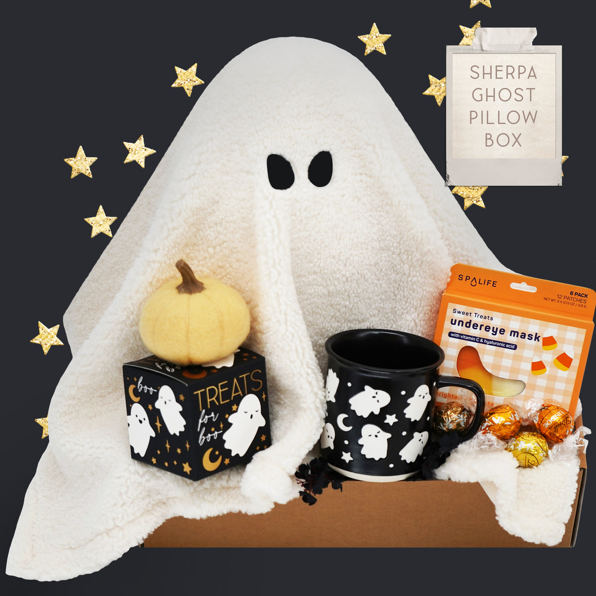 Halloween-themed gift set with ghost pillow, pumpkin, Wildflower Pop Ghost mug, and candy on a dark background.