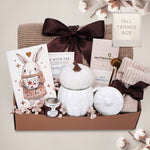 Gift basket with a blanket, drink sampler, and decorative items on a light gray background