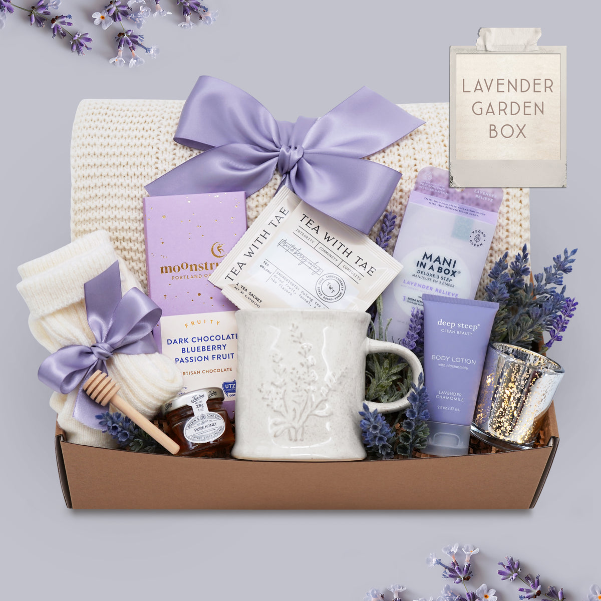 Lavender Garden blanket gift box by Wildflower Pop comes with cream lace knit blanket, mani kit, chocolate bar, cream knit socks, mini honey and dipper, Lavender Mug by Wildflower Pop, Lavender body lotion, silver votive with tea light