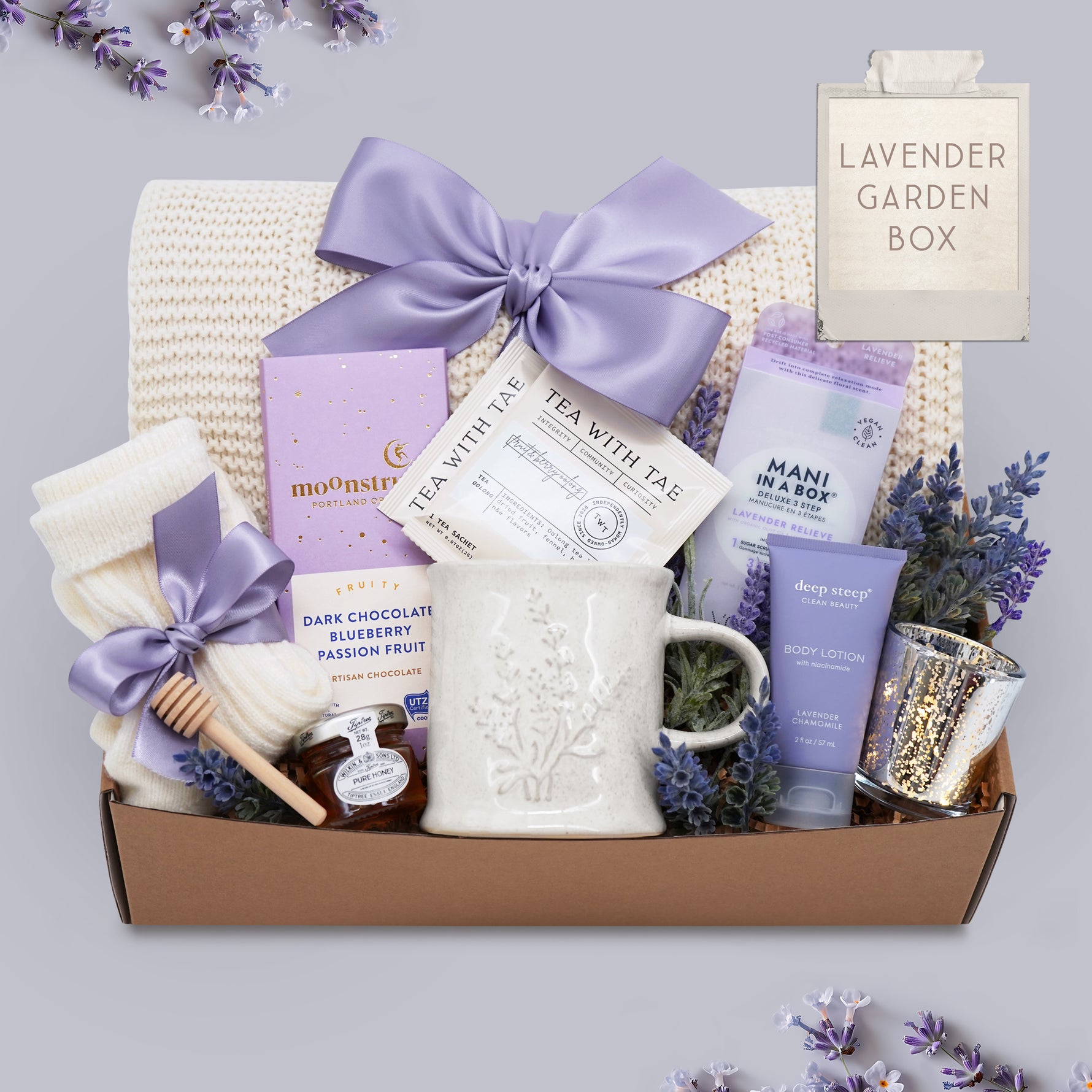 Lavender Garden blanket gift box by Wildflower Pop comes with cream lace knit blanket, mani kit, chocolate bar, cream knit socks, mini honey and dipper, Lavender Mug by Wildflower Pop, Lavender body lotion, silver votive with tea light
