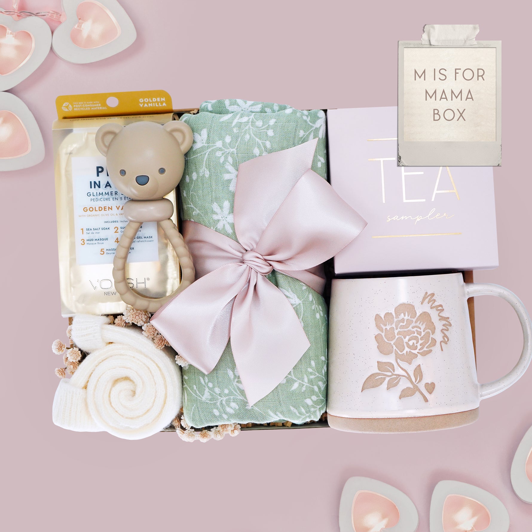 M is for Mama new mom gift set from Wildflower Pop comes with a sage green botanical swaddle, bear rattle, pedi kit, cream socks, tea sampler, and Wildflower Pop designed Peony Mama mug